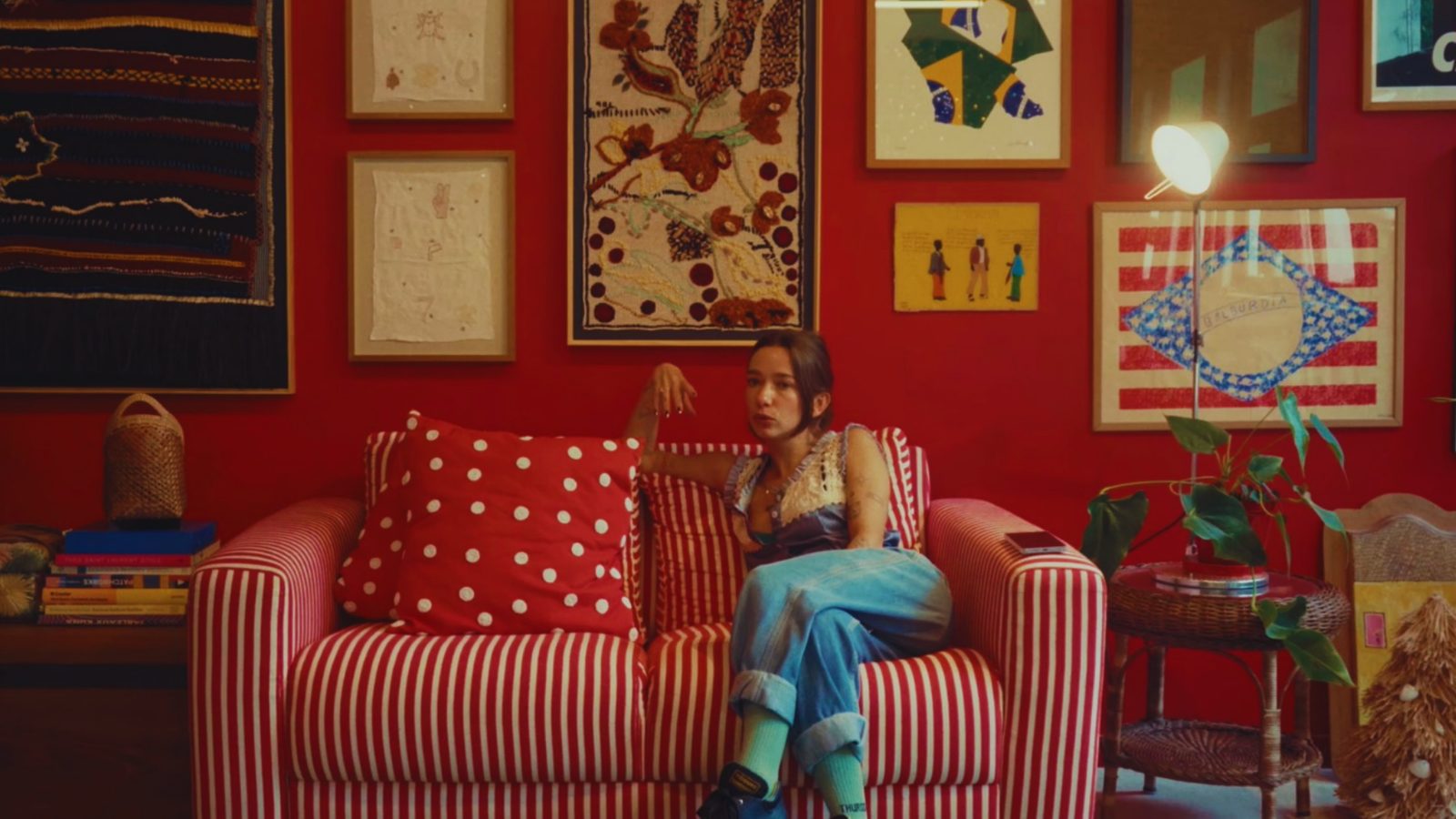 Set de filmagem: sala vermelha com sofá listrado e quadros na parede